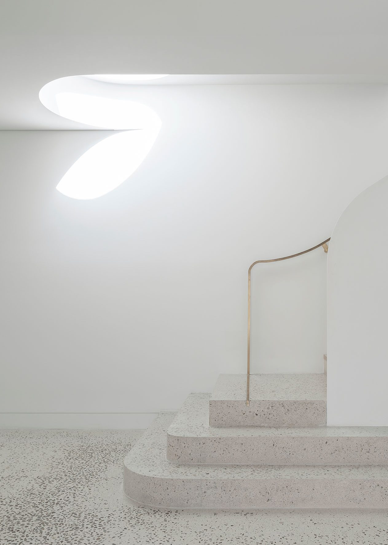 Minimal white interior with terrazzo steps and brass handrail